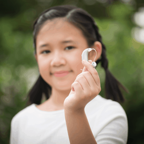 Hearing Aid Coverage for Children is Necessary: Let Nebraska Show You How Out-of-focus image of an asian girl holding up a hearing aid